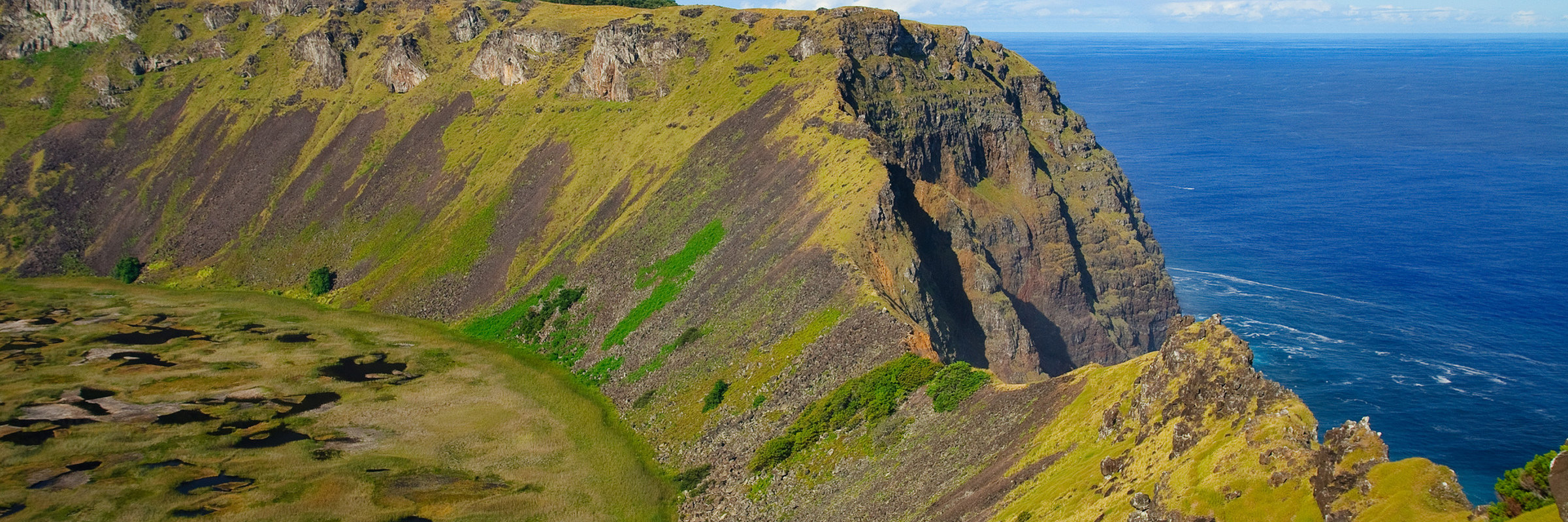 Scenic view of Rano Kau crater with steep cliffs and Pacific Ocean backdrop on Easter Island. 