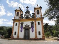Colonial baroque church of Sao Francisco in Minas Gerais, Brazil, with ornate twin towers under a blue sky. 