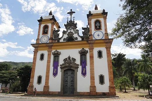 Colonial baroque church of Sao Francisco in Minas Gerais, Brazil, with ornate twin towers under a blue sky. 