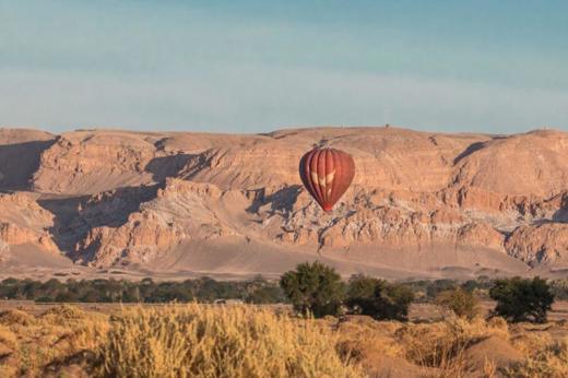 Hot air balloon soaring over the desert landscape of San Pedro de Atacama, offering sweeping views of Chile's arid terrain. 