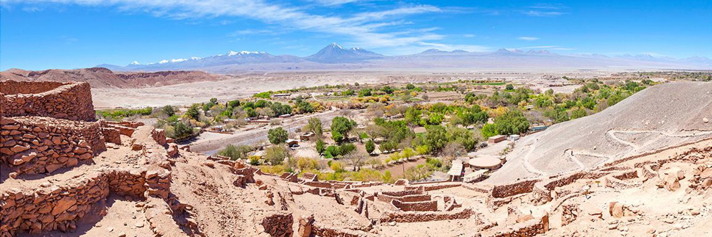Ancient stone ruins overlooking an oasis with the Andes in the background near San Pedro de Atacama. 