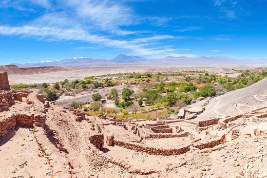 Ancient stone ruins overlooking an oasis with the Andes in the background near San Pedro de Atacama. 