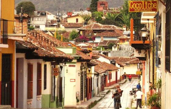 Cobbled street in San Cristobal de las Casas, Mexico, with colonial buildings, colourful facades, and locals walking. 