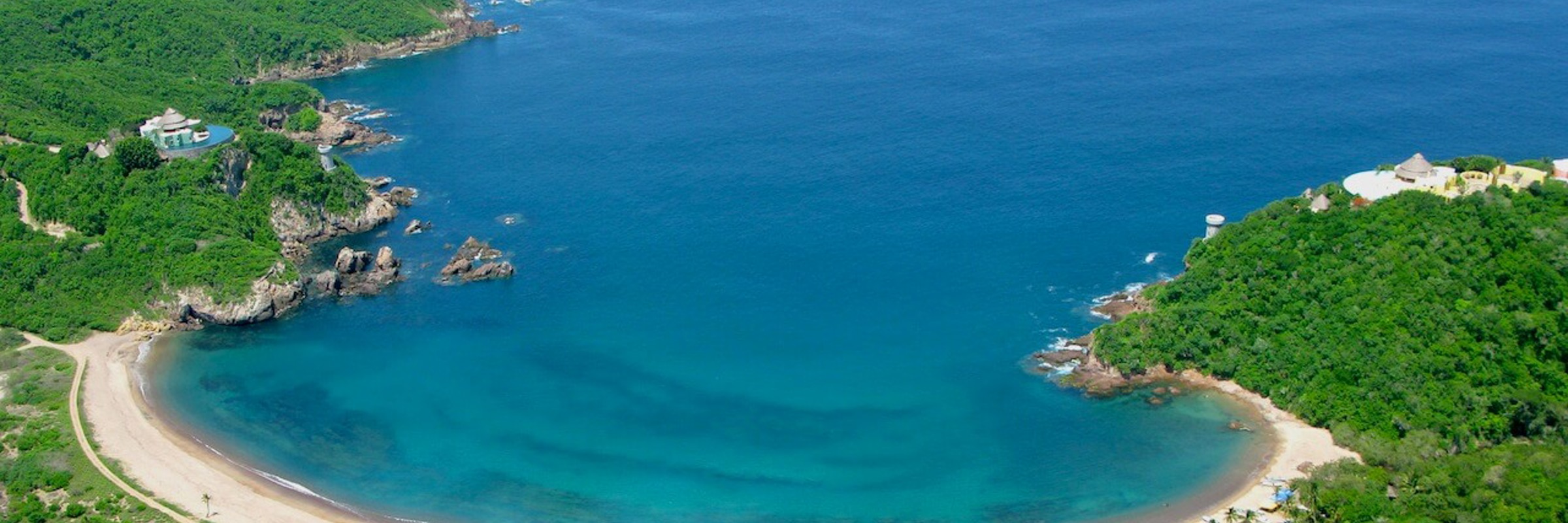 Aerial view of Costa Careyes, showcasing a secluded crescent-shaped beach and lush greenery along Mexico's Pacific Coast. 
