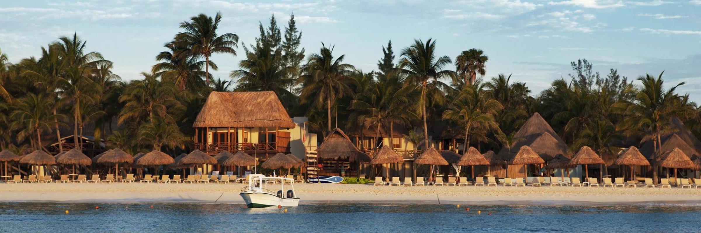 Beachfront palapas and palm trees at Playa del Carmen on the Riviera Maya, Mexico with turquoise Caribbean Sea views. 