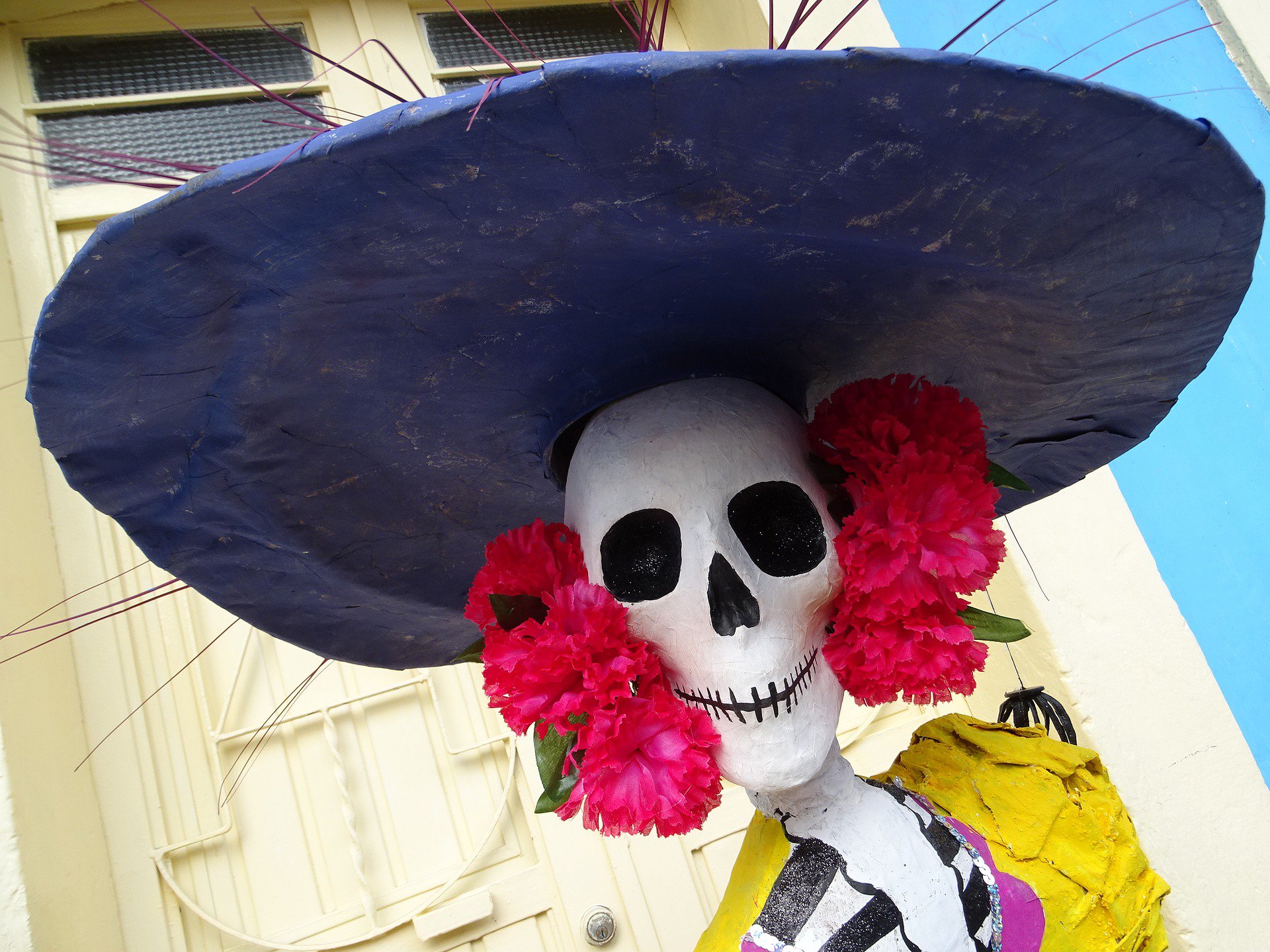 Colourful Day of the Dead Catrina figure with wide hat and flowers, part of Mexico's Dia de los Muertos celebrations. 