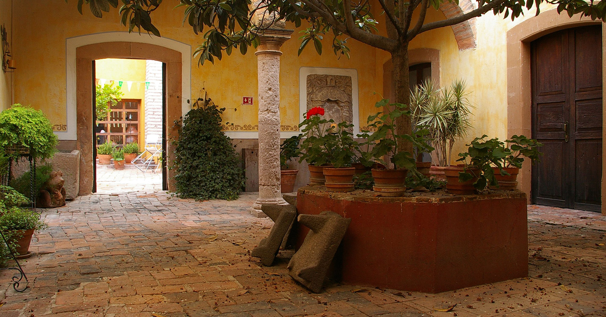 Tranquil courtyard with colonial arches, potted plants, and stone flooring at a traditional hacienda in the Yucatan, Mexico. 