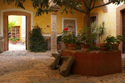 Tranquil courtyard with colonial arches, potted plants, and stone flooring at a traditional hacienda in the Yucatan, Mexico. 