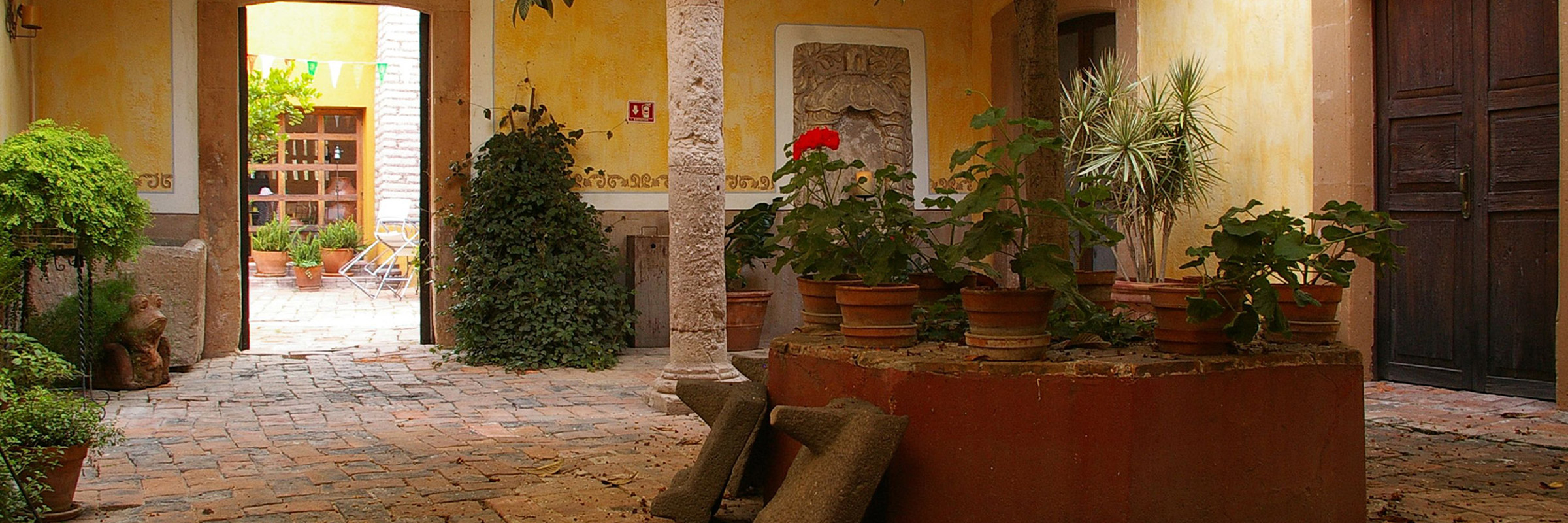 Tranquil courtyard with colonial arches, potted plants, and stone flooring at a traditional hacienda in the Yucatan, Mexico. 