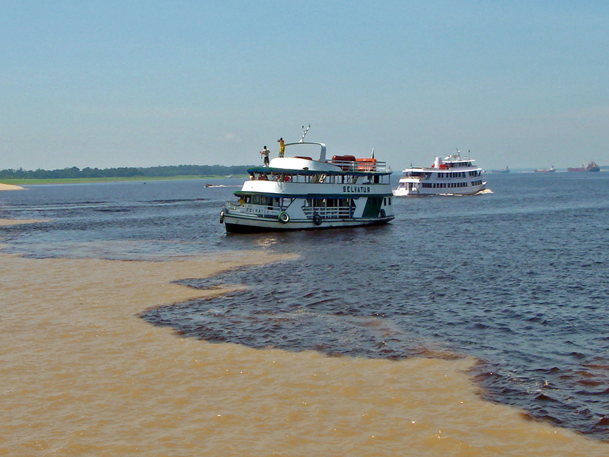 Tour boats at the Meeting of the Waters where the Rio Negro and Solimoes Rivers meet near Manaus, Brazil. 