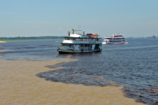 Tour boats at the Meeting of the Waters where the Rio Negro and Solimoes Rivers meet near Manaus, Brazil. 