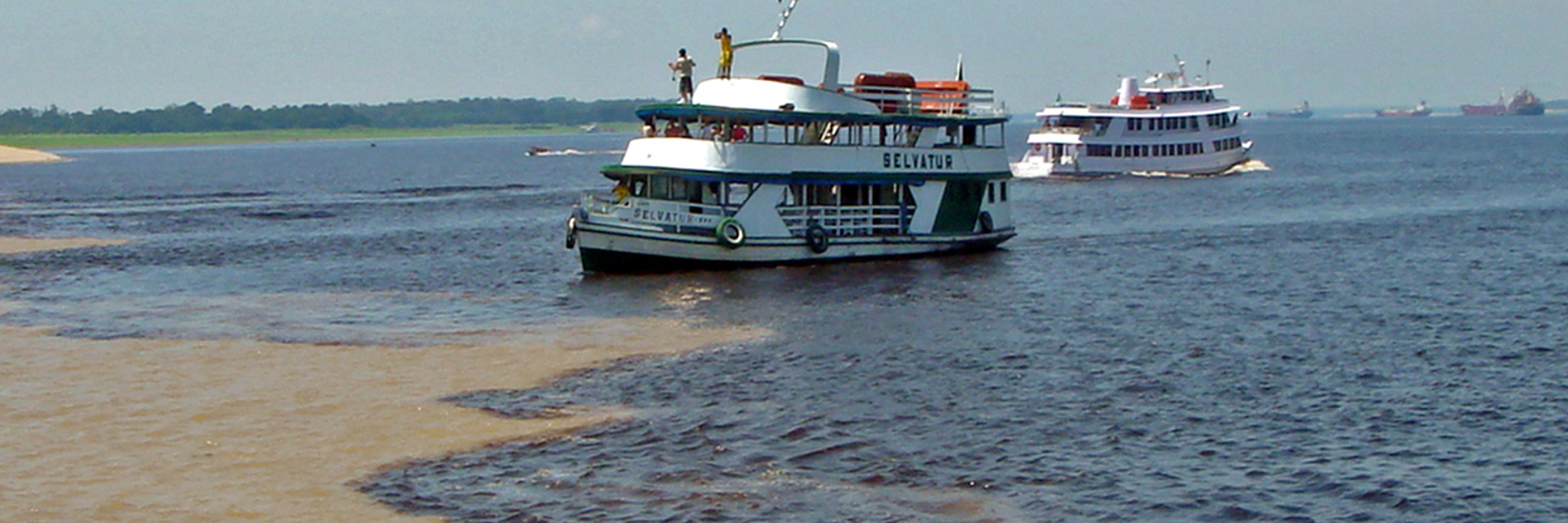 Tour boats at the Meeting of the Waters where the Rio Negro and Solimoes Rivers meet near Manaus, Brazil. 