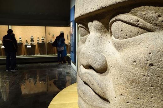 olmec colossal head and visitors at the National Museum of Anthropology, Mexico City, showcasing ancient Mesoamerican artifacts. 
