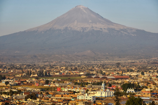 View of the Popocatepetl Volcano behind the Great Pyramid of Cholula and its hilltop church, near Puebla, Mexico. 