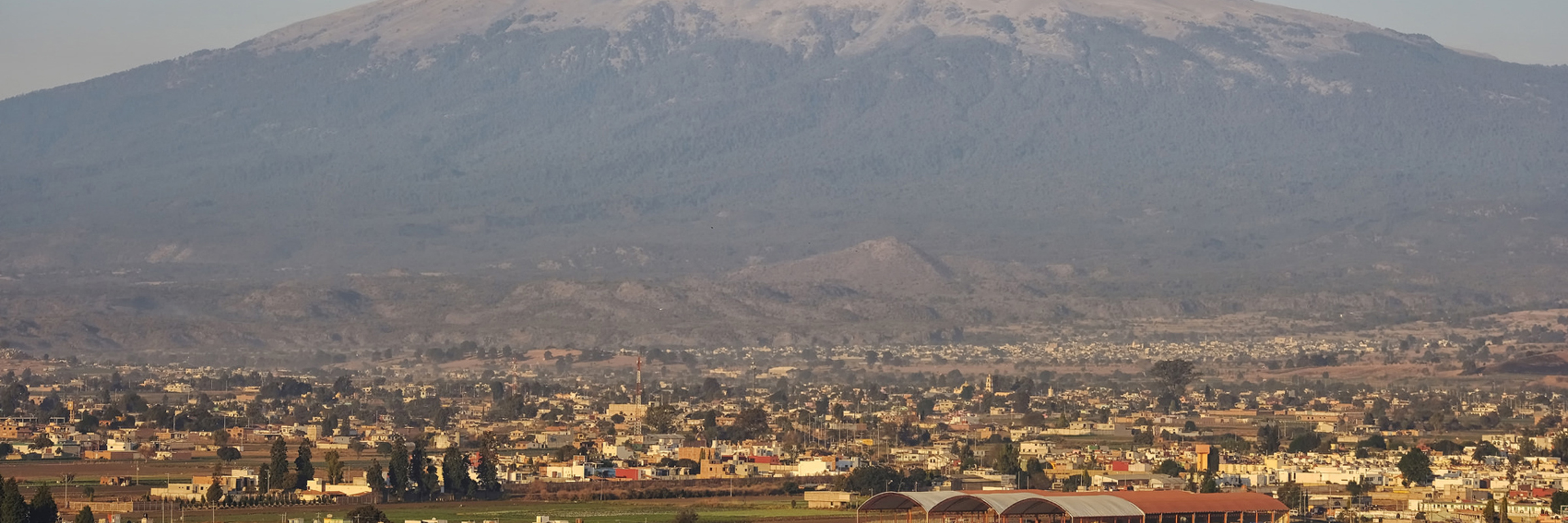 View of the Popocatepetl Volcano behind the Great Pyramid of Cholula and its hilltop church, near Puebla, Mexico. 