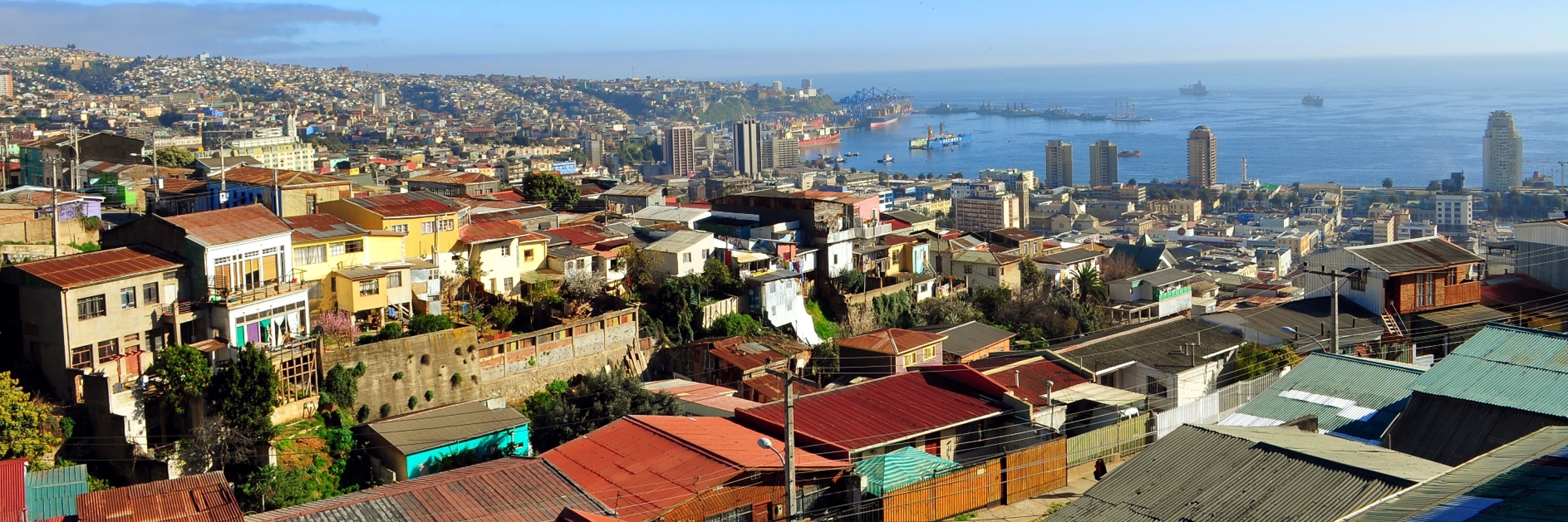 Colorful hillside homes overlook the bustling port and bay of Valparaiso under clear blue skies on Chile's Pacific coast. 