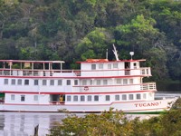 The Tucano Amazon cruise boat on the Rio Negro surrounded by lush rainforest, near Manaus, Brazil. 