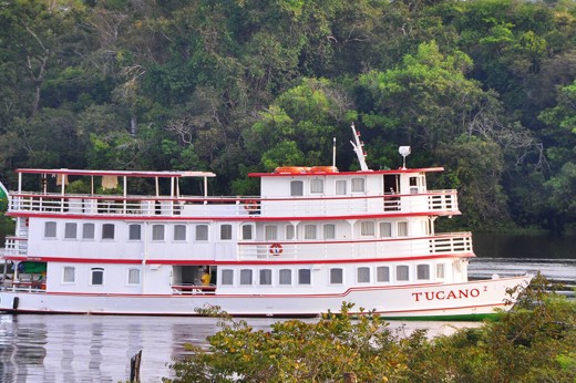The Tucano Amazon cruise boat on the Rio Negro surrounded by lush rainforest, near Manaus, Brazil. 