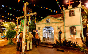 Colourful June Festival night scene with a chapel, wooden cross, and hanging flags in Brazil's Festa Junina. 