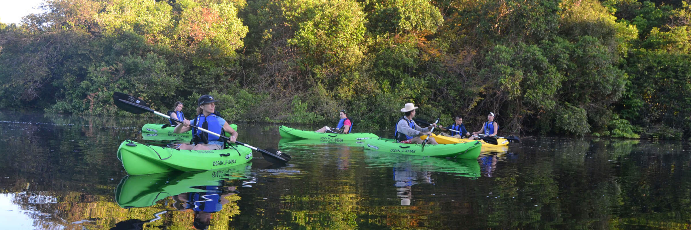 Travelers kayaking through a calm jungle river during an Amazon expedition cruise in Brazil. 