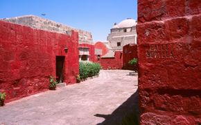 A quiet walkway lined with vivid red walls at Arequipa's Santa Catalina Convent. 