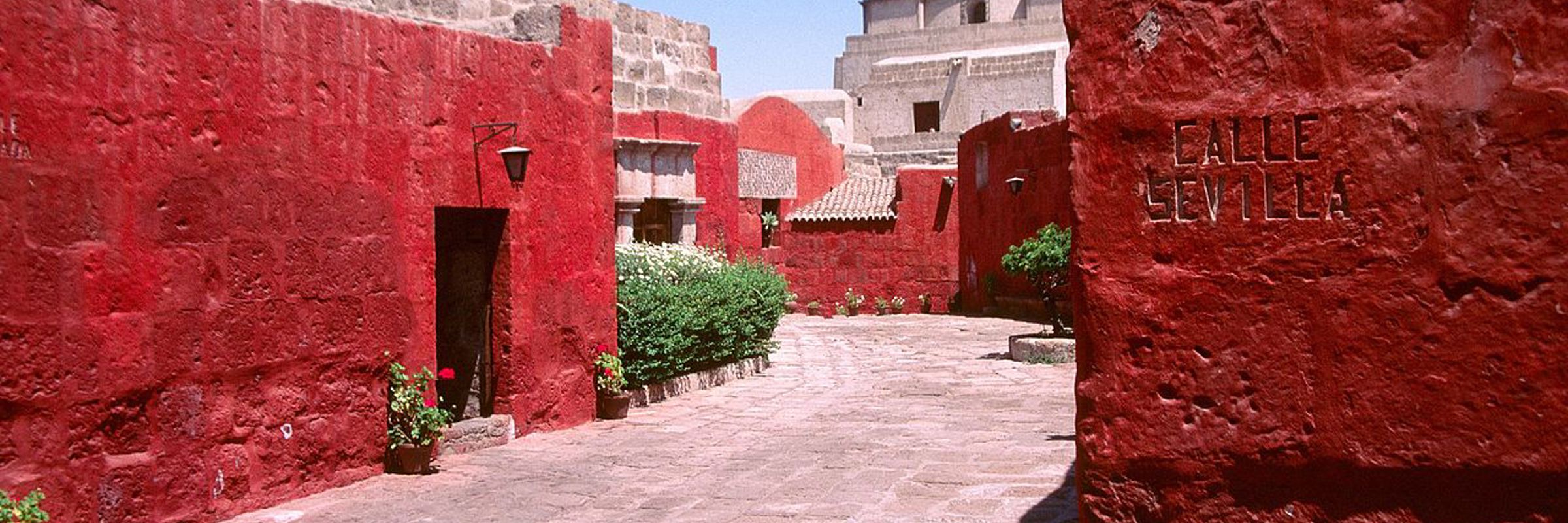 A quiet walkway lined with vivid red walls at Arequipa's Santa Catalina Convent. 