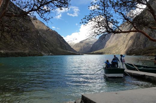 Scenic lake in Huaraz with mountains and boat under a clear sky in the Peruvian Andes. 