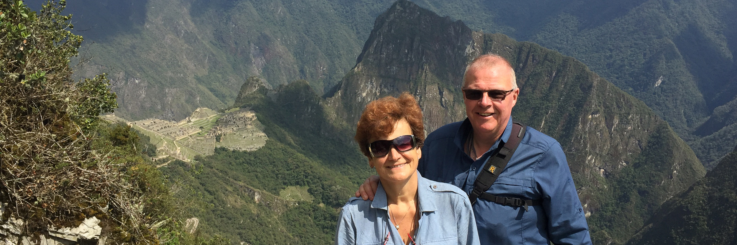 A smiling couple poses at a sunny Machu Picchu viewpoint, a perfect Peru postcard moment. 