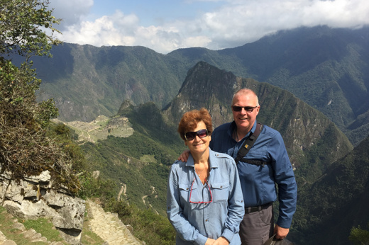 A smiling couple poses at a sunny Machu Picchu viewpoint, a perfect Peru postcard moment. 
