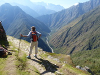 Hiker enjoying panoramic views along the Inca Trail in Peru with mountains stretching into the distance. 
