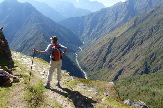 Hiker enjoying panoramic views along the Inca Trail in Peru with mountains stretching into the distance. 