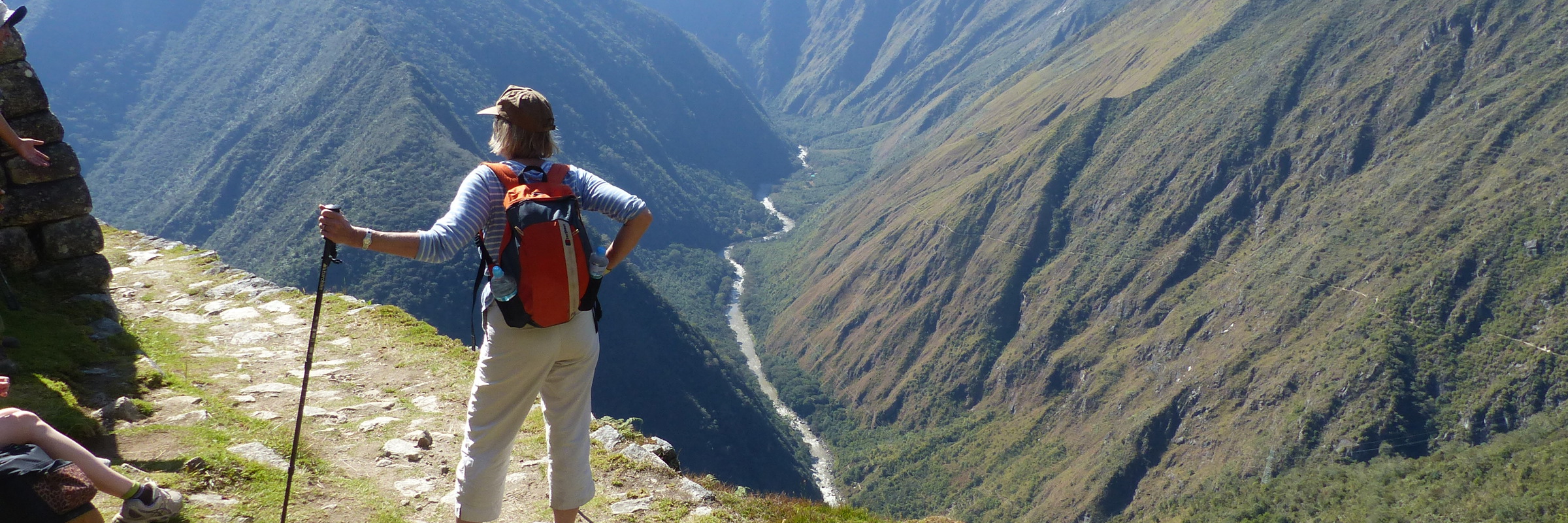 Hiker enjoying panoramic views along the Inca Trail in Peru with mountains stretching into the distance. 