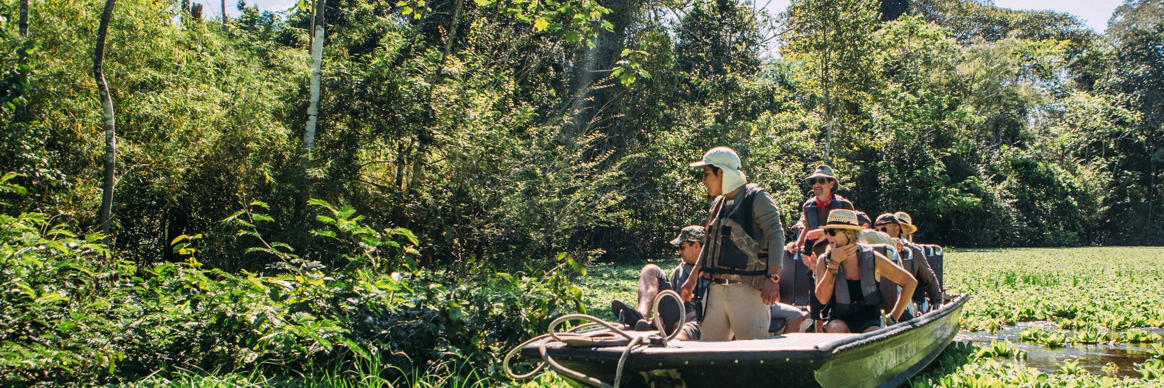 Tourists on a guided boat tour exploring the Amazon jungle and wildlife in Peru. 