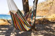 Relaxing in a colourful hammock strung between palm trees on a quiet tropical beach. 