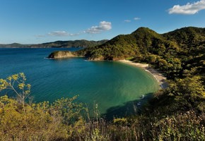 A tranquil bay framed by lush forested hills, offering stunning views of Costa Rica's unspoiled coastline. 