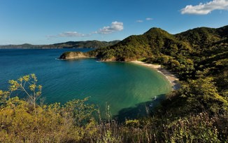 A tranquil bay framed by lush forested hills, offering stunning views of Costa Rica's unspoiled coastline. 