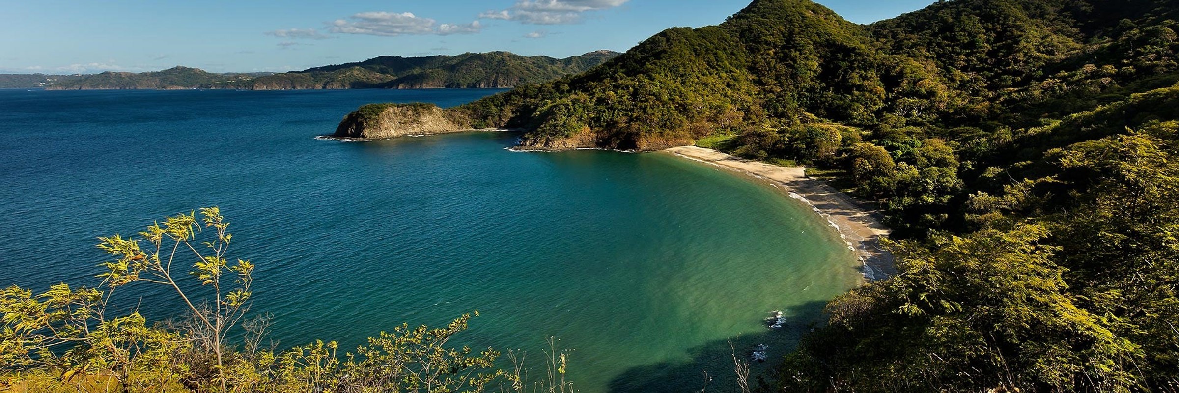 A tranquil bay framed by lush forested hills, offering stunning views of Costa Rica's unspoiled coastline. 