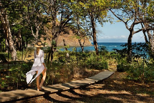 Woman walking along a forest path towards the ocean at Kasiiya, Costa Rica. 