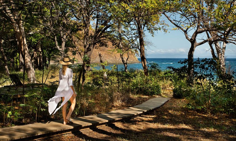 Woman walking along a forest path towards the ocean at Kasiiya, Costa Rica. 