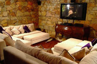 Cozy Ingenuity Room with plush seating, stone walls, and TV at Ibitipoca Reserve, Brazil. 