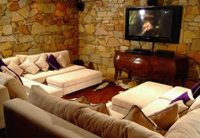 Cozy Ingenuity Room with plush seating, stone walls, and TV at Ibitipoca Reserve, Brazil. 