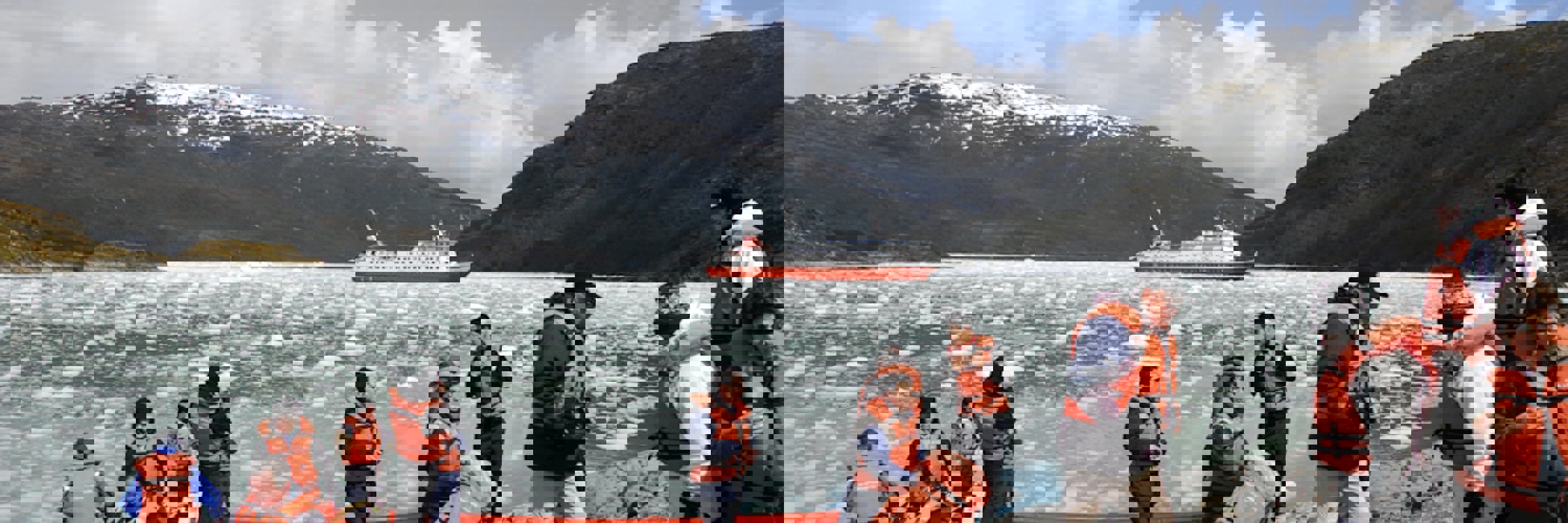 Tourists in life jackets disembark from Zodiacs onto an icy shoreline during a glacier expedition cruise in Chilean Patagonia. 
