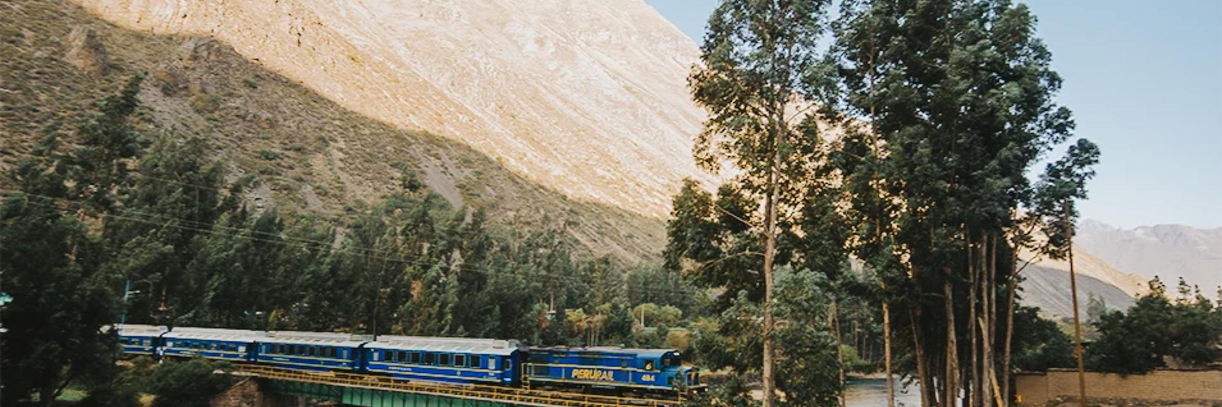 Expedition train crossing a scenic bridge with the Andes mountains in the background on the route to Machu Picchu. 