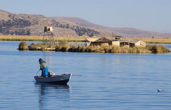 A local fisherman rows past reed islands on the tranquil blue waters of Lake Titicaca. 