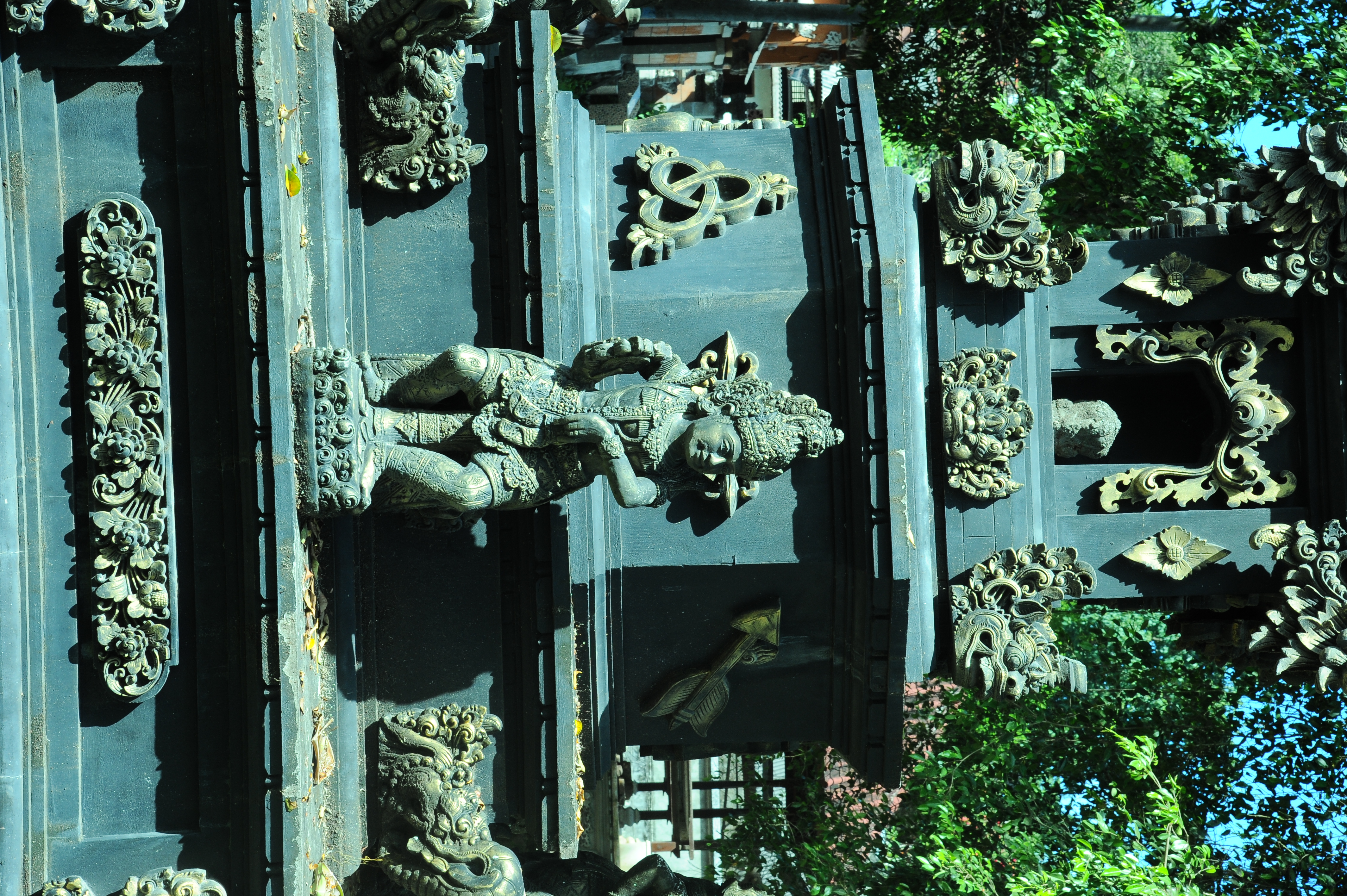 A detailed Balinese temple sculpture stands among ornate carvings in a sacred courtyard in Bali, Indonesia. 