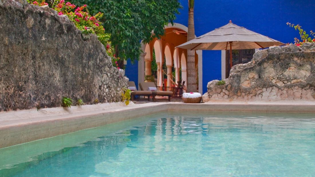 Private pool at luxury presidential suite in Mexico, surrounded by tropical gardens and a shaded palapa seating area. 