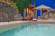 Private pool at luxury presidential suite in Mexico, surrounded by tropical gardens and a shaded palapa seating area. 