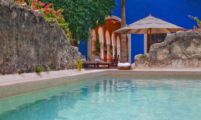 Private pool at luxury presidential suite in Mexico, surrounded by tropical gardens and a shaded palapa seating area. 