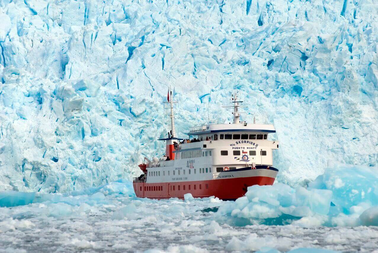 The Skorpios II cruise ship approaches the towering blue ice wall of a glacier in Chilean Patagonia. 