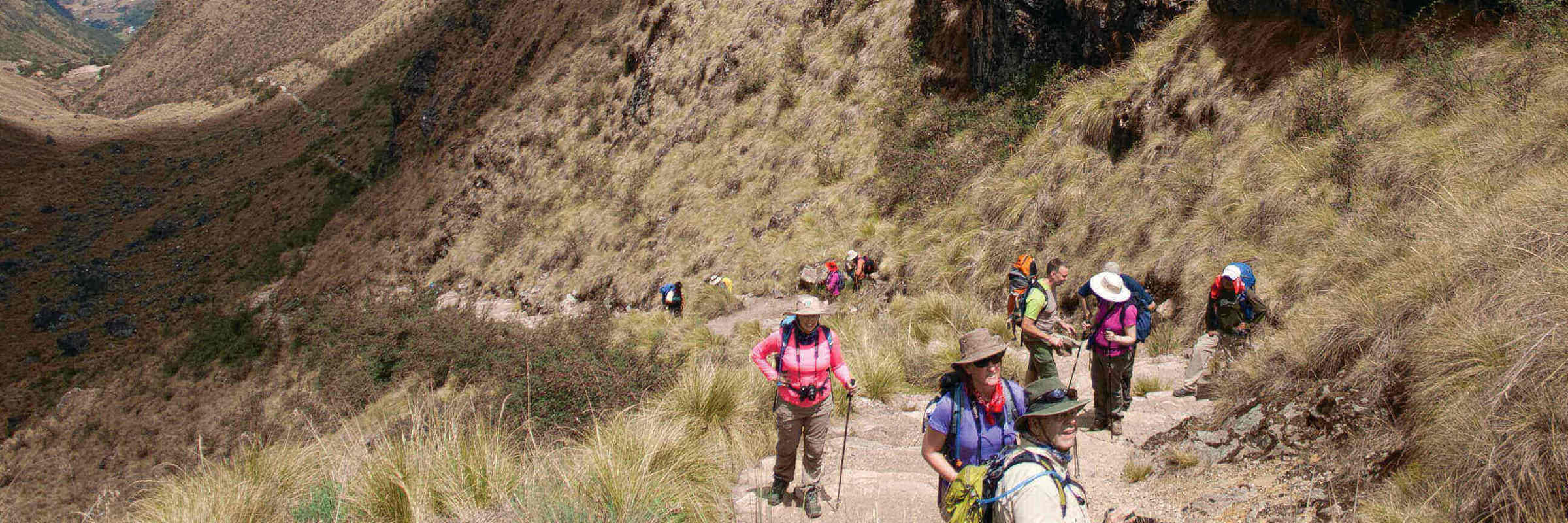 Hikers and porters trekking through a high mountain pass on the Inca Trail in Peru's Sacred Valley. 